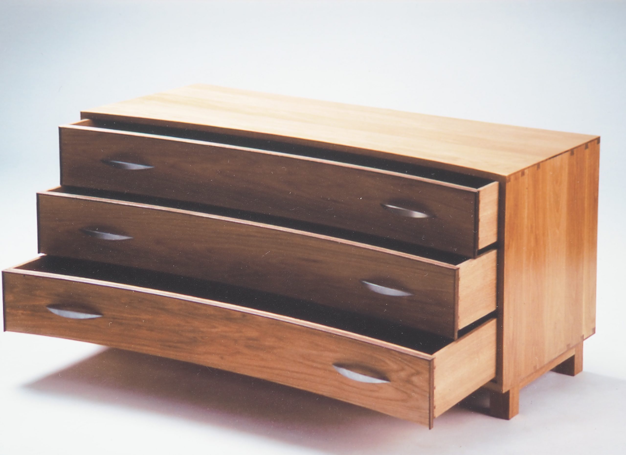 Concave chest of drawers with lipped dovetail construction. Made in chestnut with walnut cock-beading. Three dovetailed drawers with cedar bottoms finish of this timeless peace of furniture.